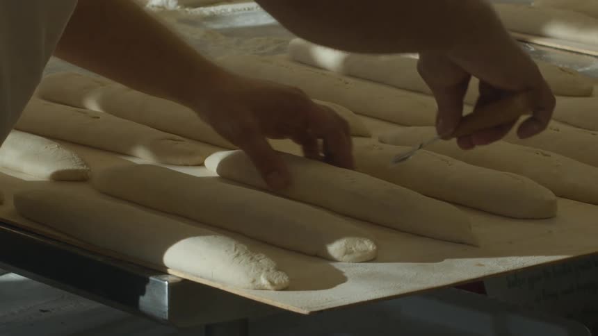 A baker preparing bread dough on a flour covered tabletop
