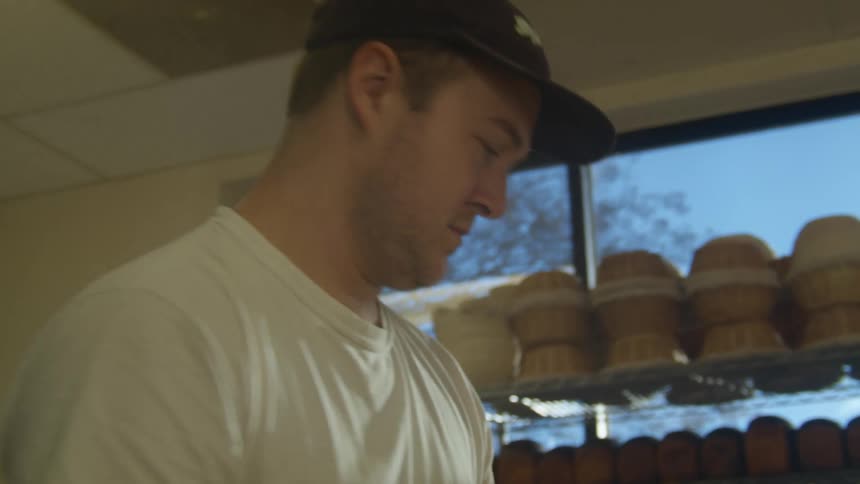 A man putting bread dough into a pan in a bakery