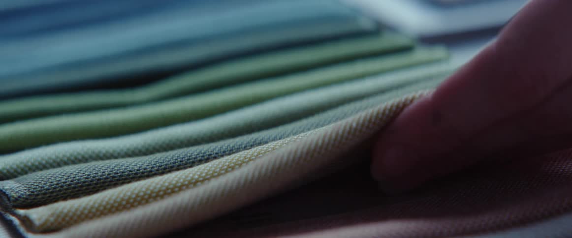A person touching different fabrics on a table