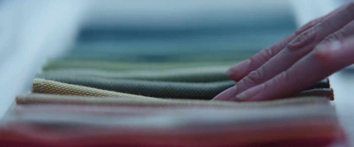 A person touching different fabrics on a table