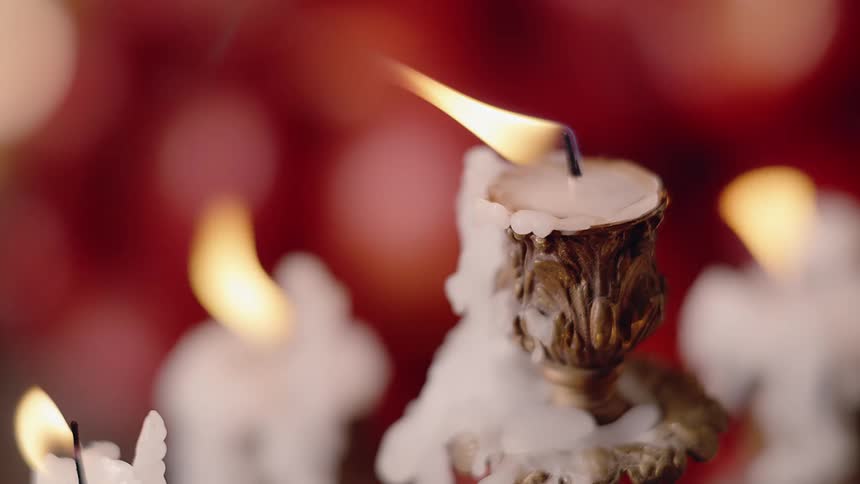 Flame burns in melted white candles against red background