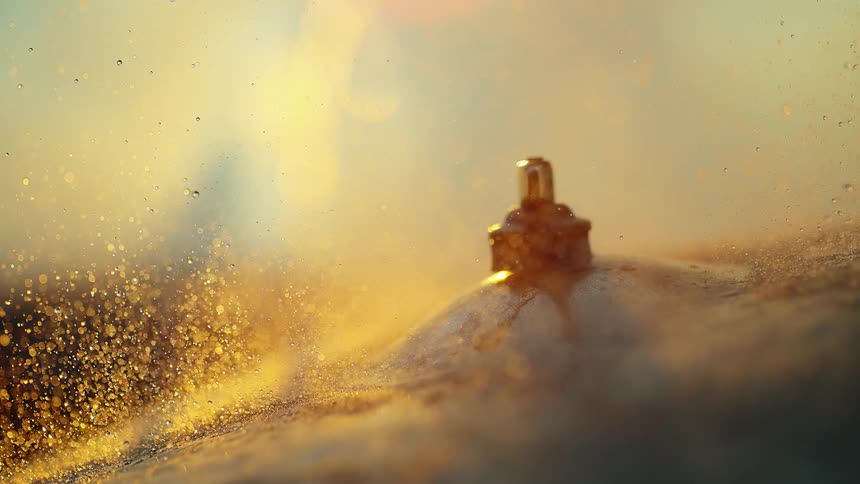 Light reflects from wet cymbal vibrating and splashing water droplets into air as it is struck by drum stick