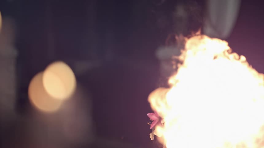 A woman is doing a magic trick outdoors with fire