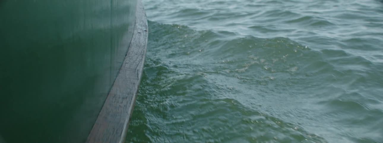 A boat hull reflects the waves as it moves through the water