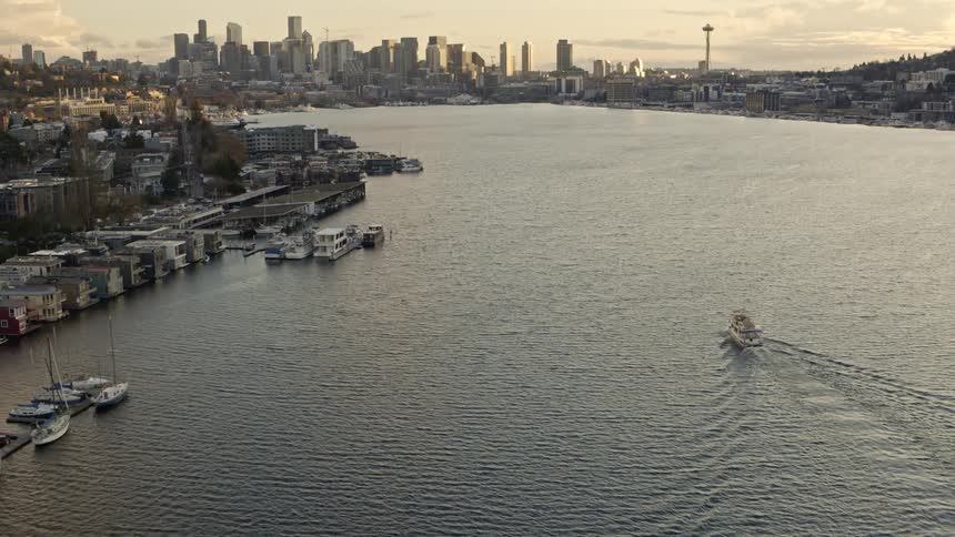 Flying above houseboats along the Eastlake shoreline as a small yacht makes its way toward downtown Seattle