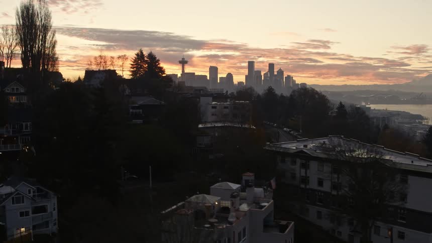 Reveal of the Seattle skyline and Mount Rainier during a stunning sunrise from behind condos and homes along Queen Anne hill
