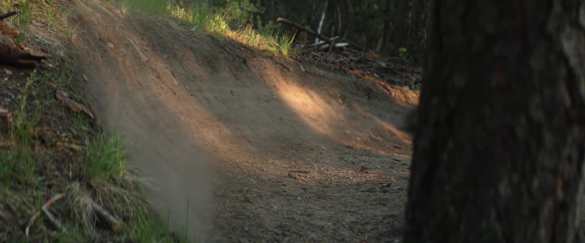 Cyclist rides bicycle through fast dusty corner on mountain bike trail