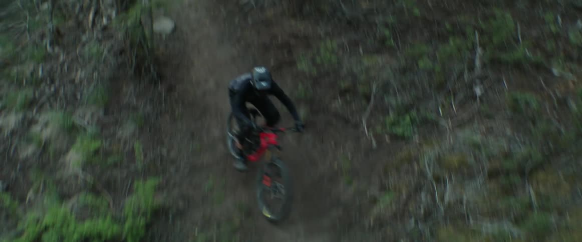 A professional mountain bike athlete races through back to back corners on dirt trail