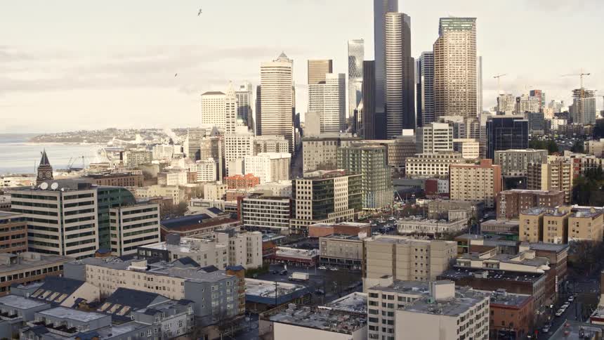 Flying toward high-rise buildings as traffic flows along downtown streets