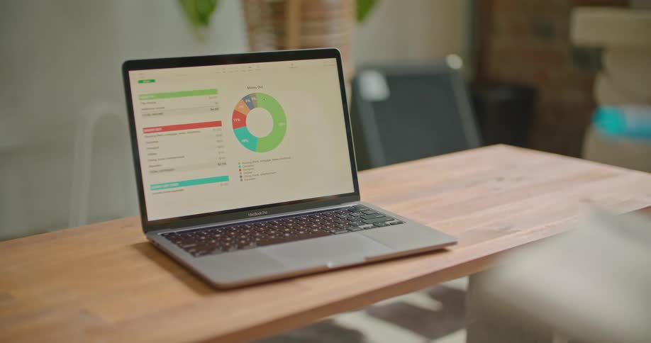 A laptop on a wooden table displays a colored chart and graph