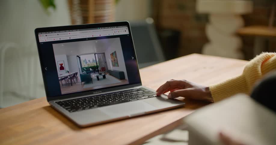 A woman looks through images of real estate listings on her laptop