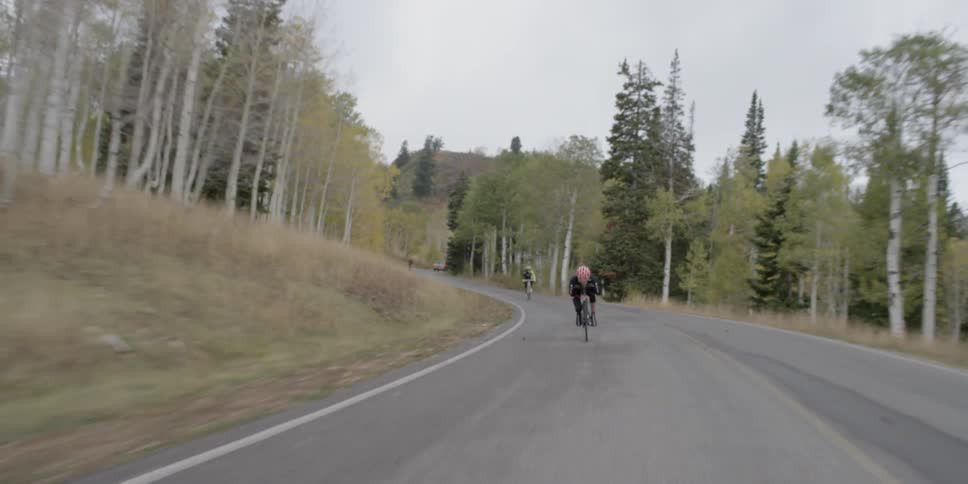 Two people are racing down a road on bikes