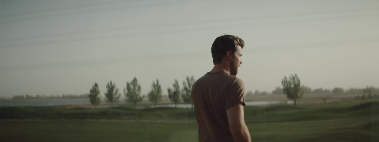 A man is talking outside by the long field