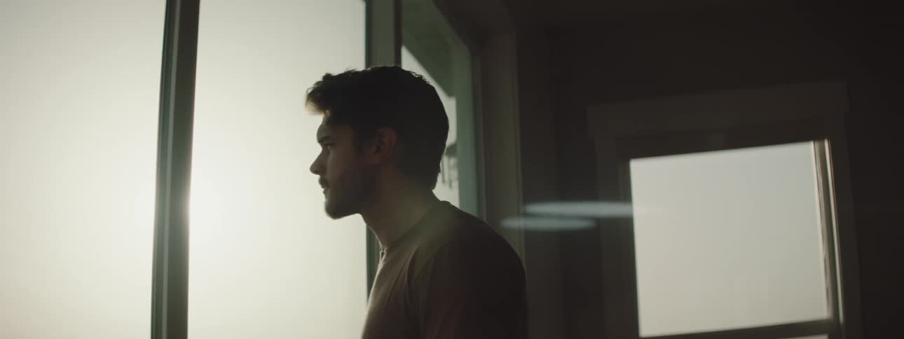 A man stands looking out the window