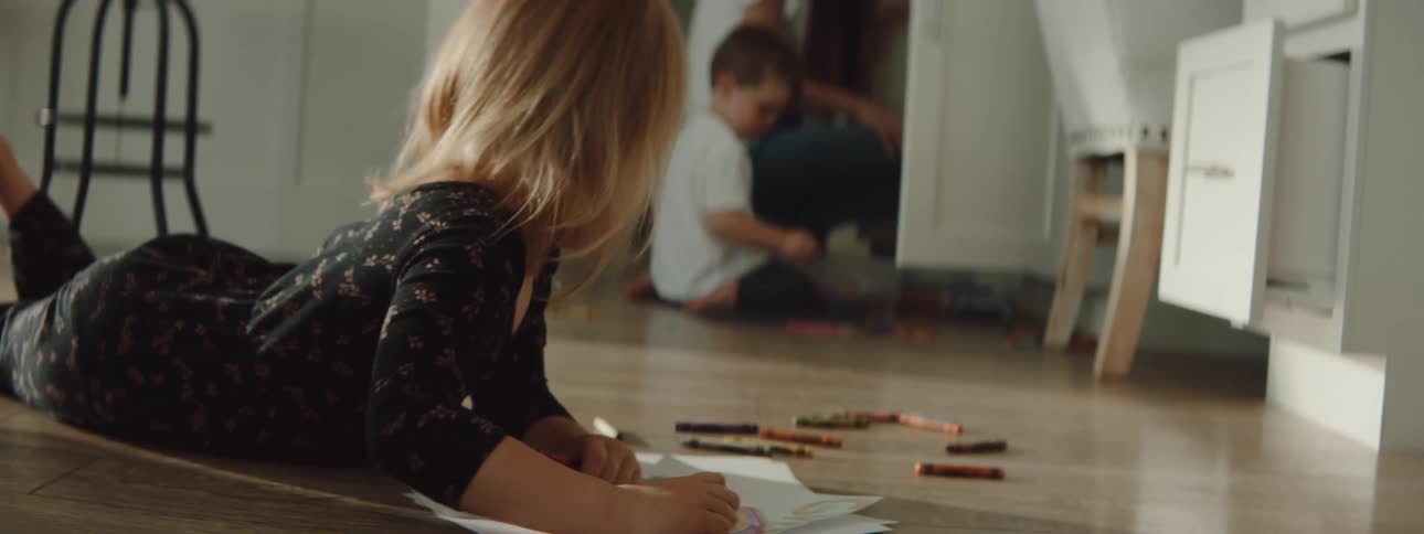Brother and sister are drawing pictures and playing indoors
