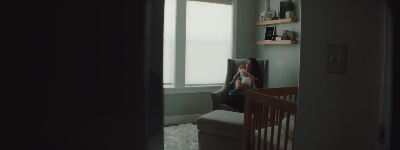 A mother sits down while holding her baby