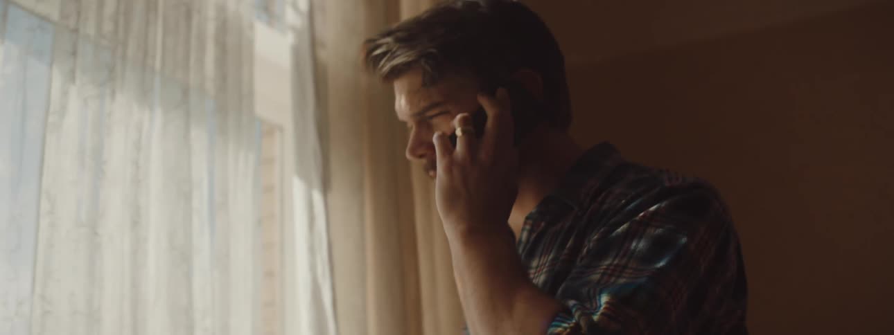A man is walking around his room and talking on a cellphone