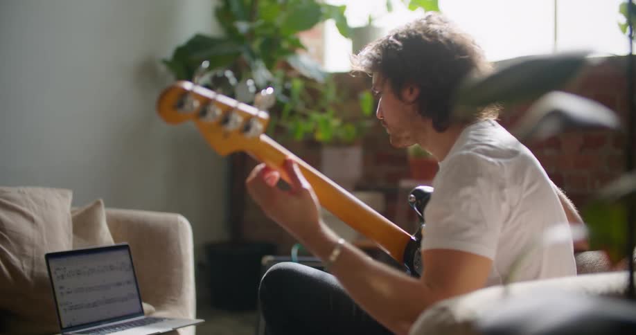 A man is reading sheet music and playing the guitar