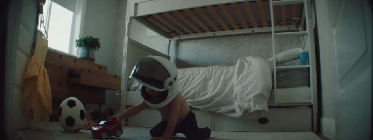 Boy wearing helmet with visor up plays on floor with toy car
