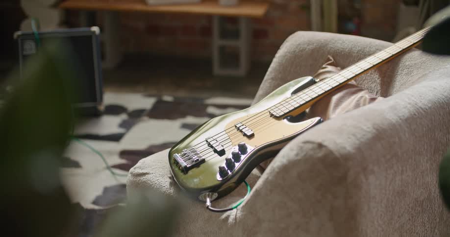 An electric guitar sits on a couch hooked up to an amp