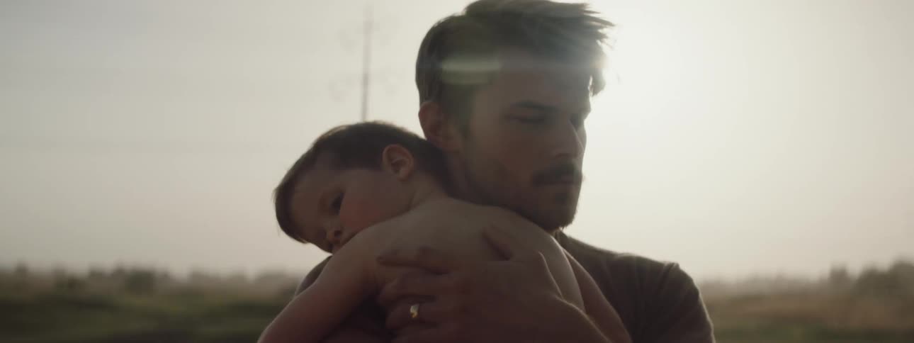 A father is holding his son outdoors at dusk