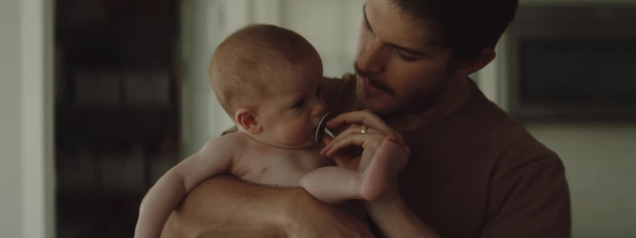 A young father holds his son in a kitchen