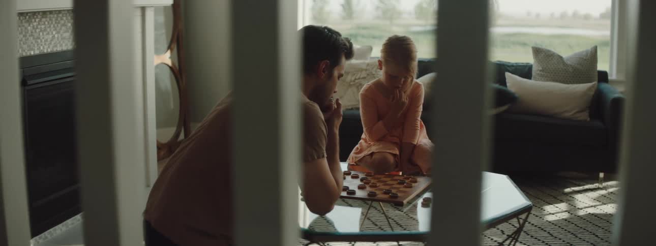 A man and daughter play a games of checkers together on a coffee table
