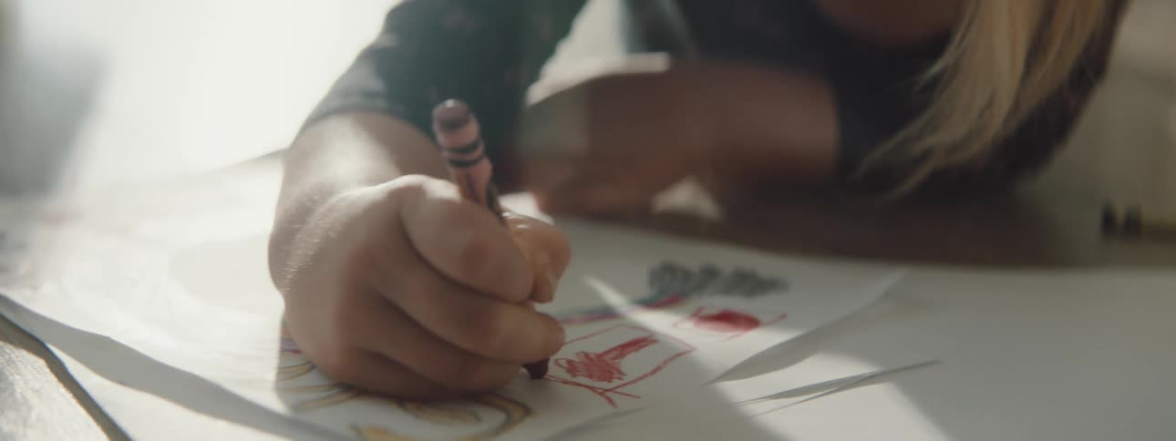 Little girl draws with a crayon while laying on the floor