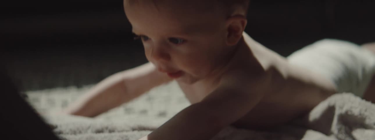 An infant is crawling on a blanket indoors
