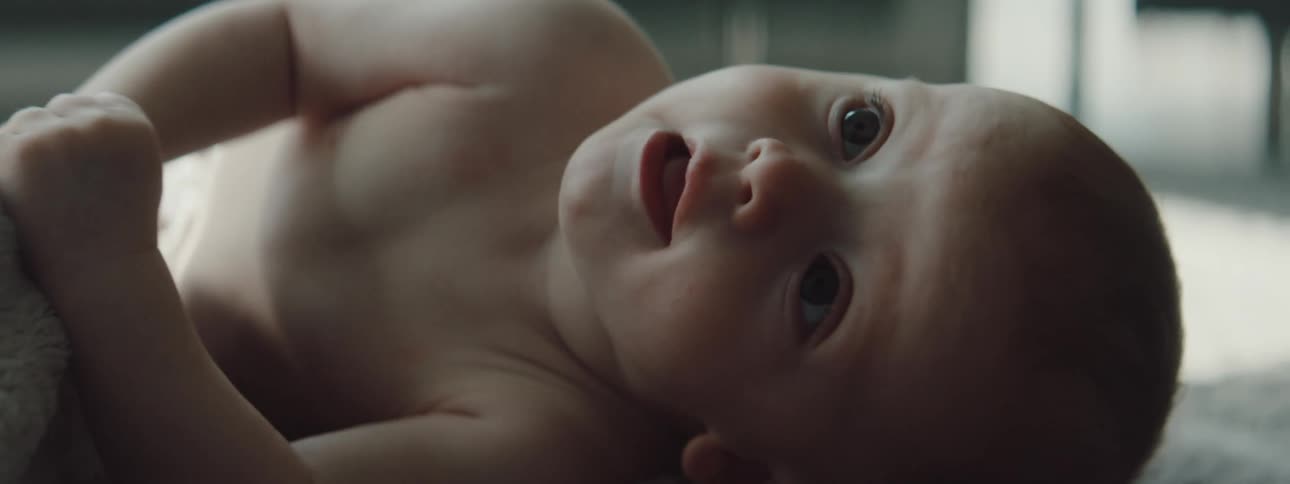 Infant laying on the floor rolls over from its back to its tummy