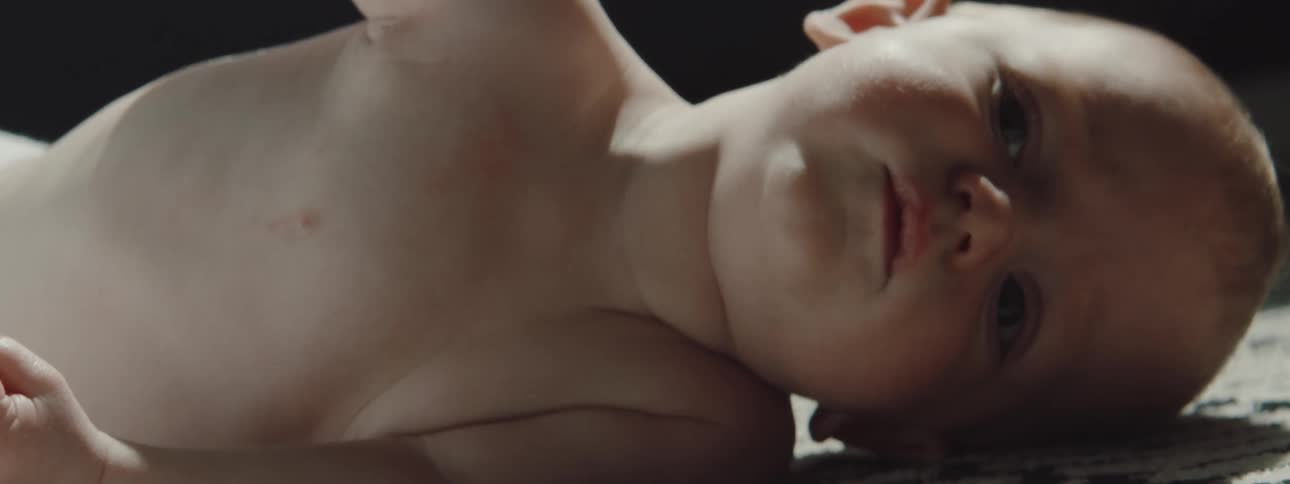 A baby lays down on the carpet