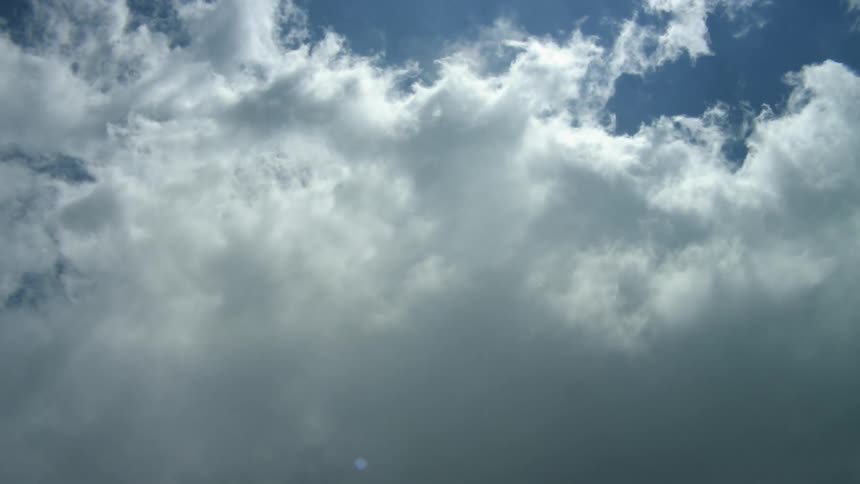 Wispy clouds move across a blue sky as they become darker