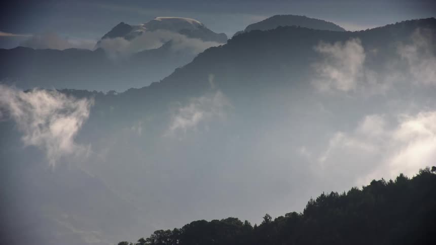Clouds floating across treed hills