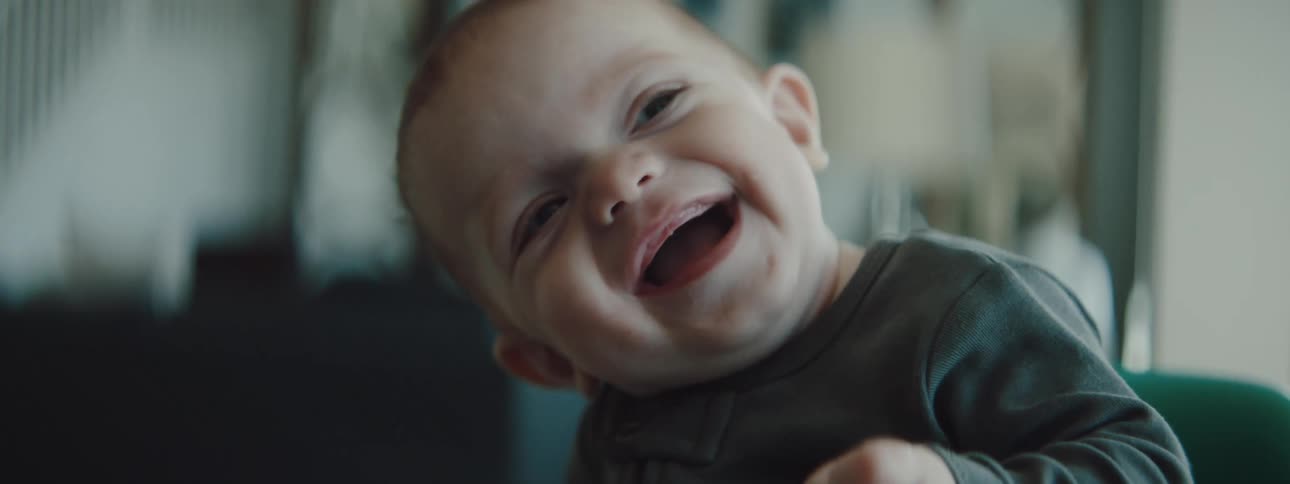 A baby is sitting in a high chair and smiling