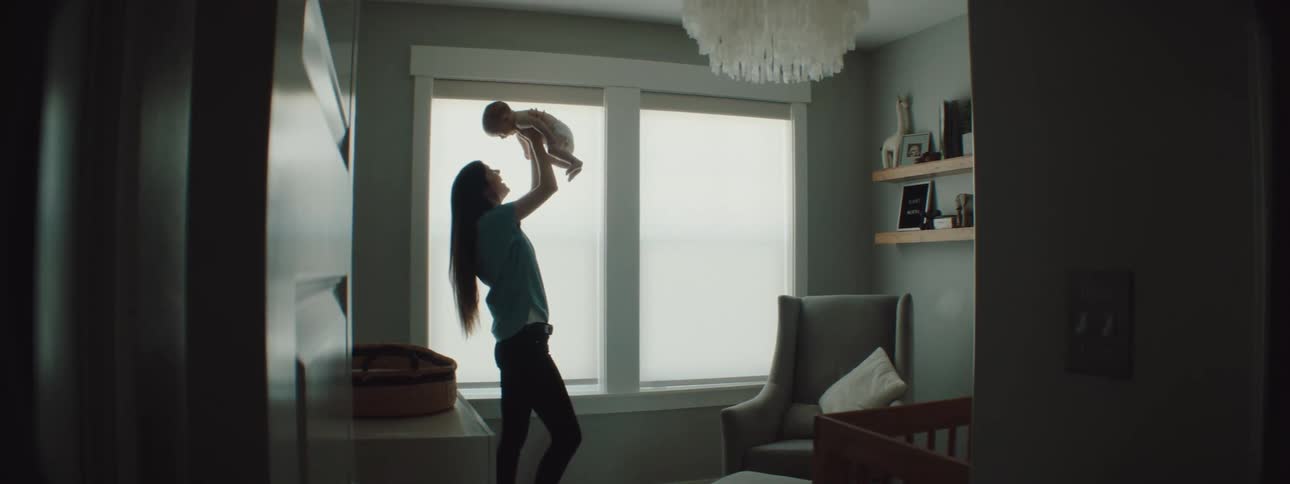 A mother is holding her child and standing in a room