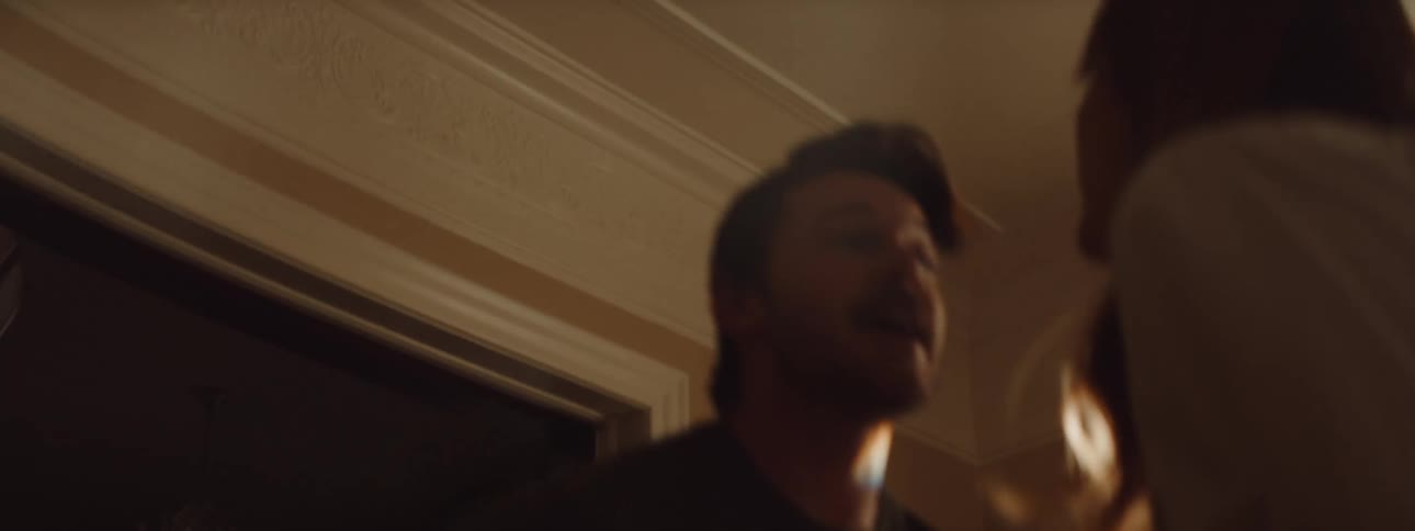 A man is playing guitar indoors and a woman is dancing