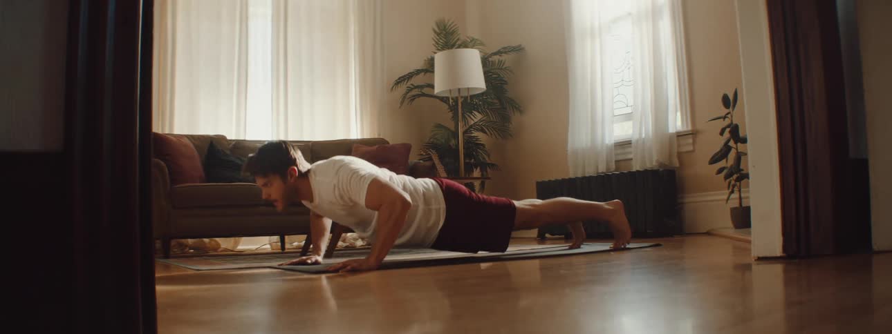 Man doing push ups over a mat in the living room at home