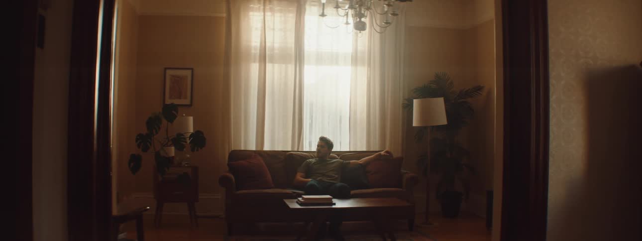 A man sits on the couch and uses his phone