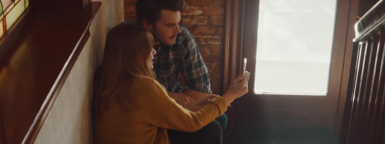 Young couple sitting in the staircase landing looking at the phone