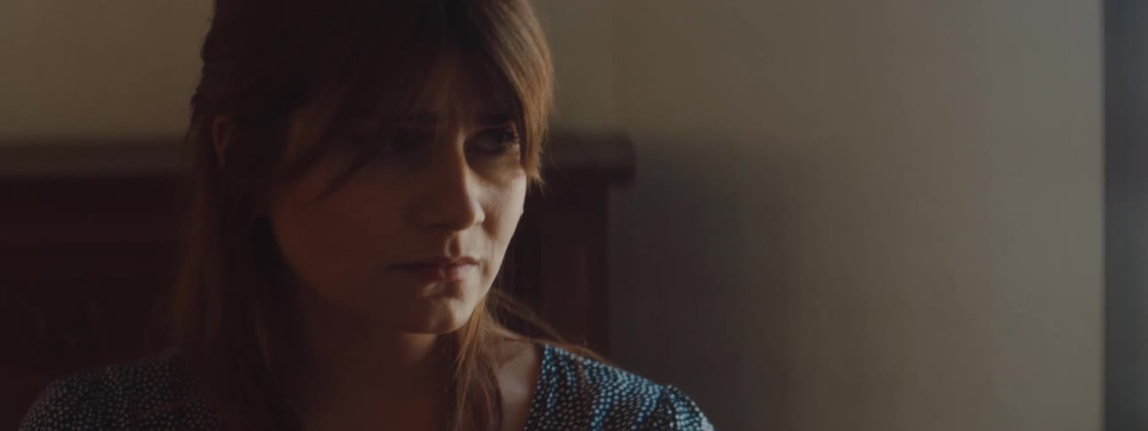 A woman at home frowns and pushes her hair out of her eyes