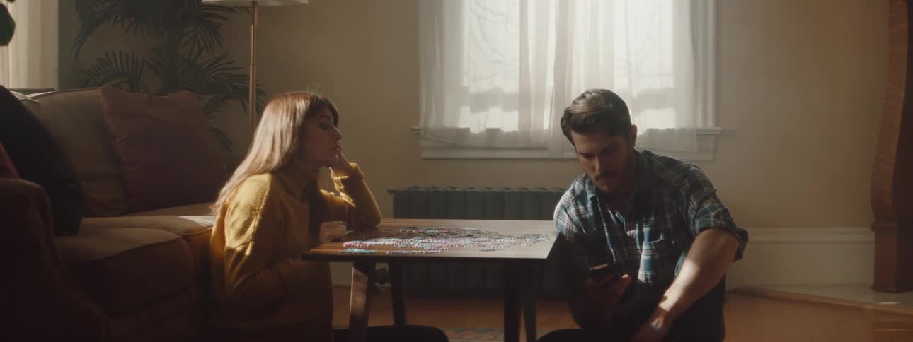 A woman throws a puzzle piece at a man checking his phone