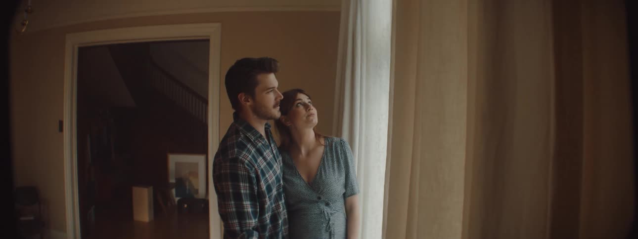 Pregnant woman smiles as man shows her into room and they look at window