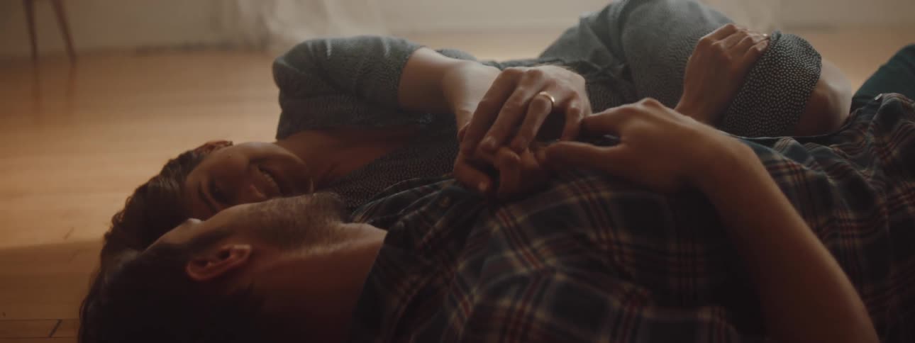 Husband and wife are laying on the ground together in their house