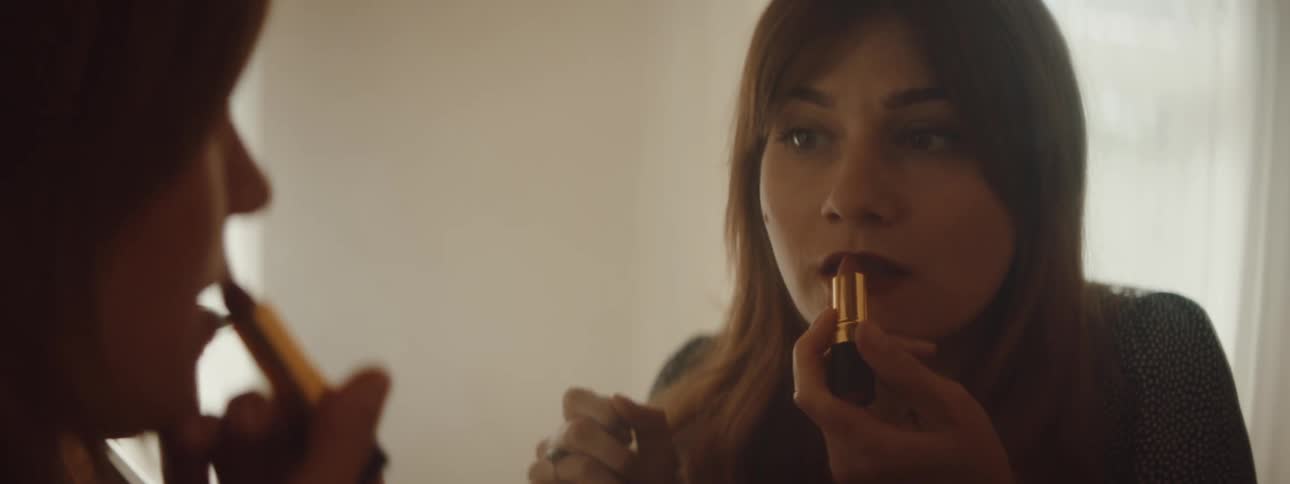 A woman is looking in a mirror and putting on makeup