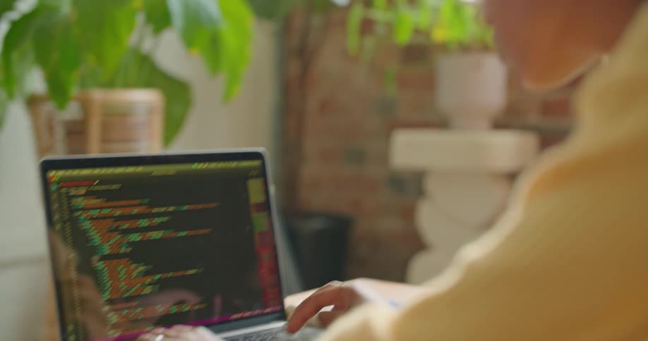 A woman is sitting at a table and typing on a laptop indoors
