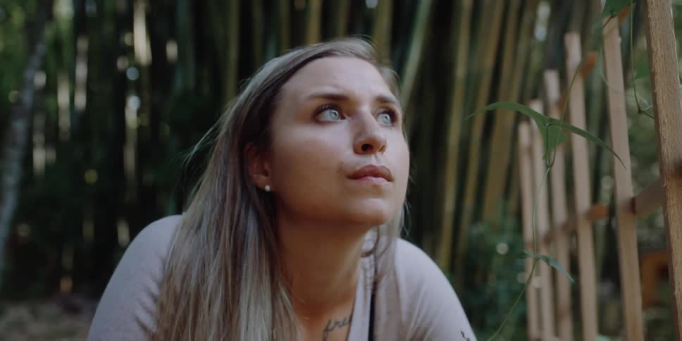 A woman is sitting outdoors by plants in spring