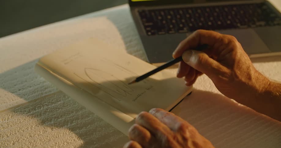 A person is drawing a figure in a notebook