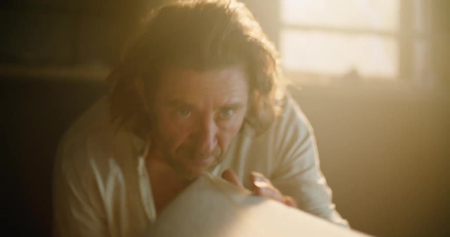 A man is working on something indoors at dusk