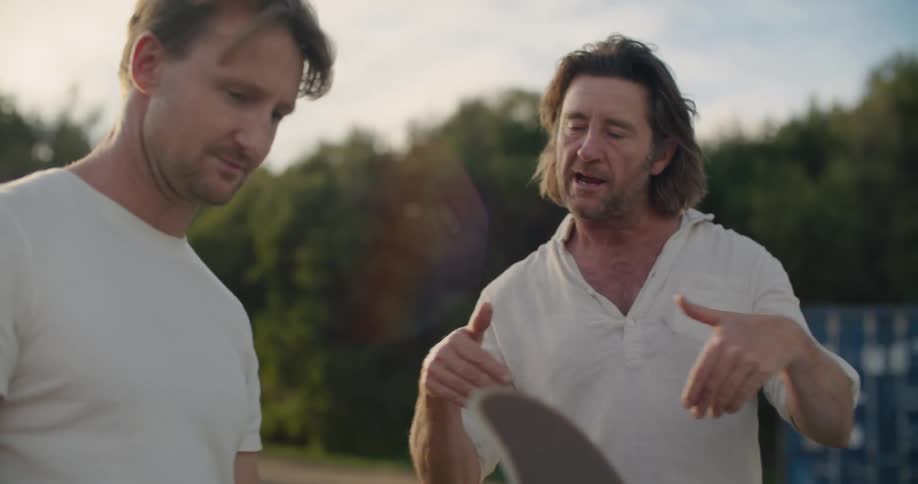 Two men talking outside around a car