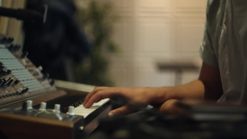 A person sitting in front of an electronic keyboard playing with the keys